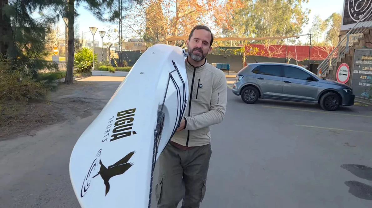 Ignacio sosteniendo el kayak Biguá Indómito con un brazo, demostrando su peso de 22 kg y facilidad de transporte
