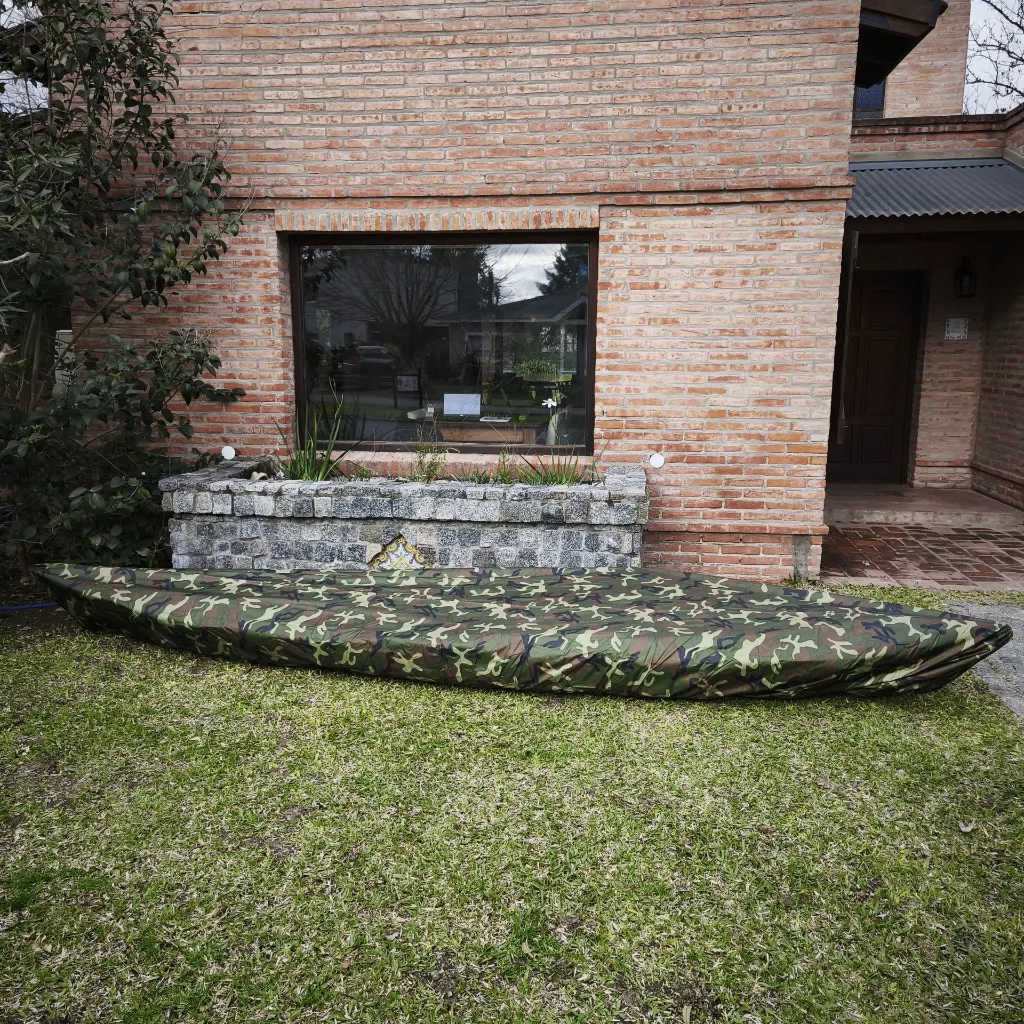 funda_kayak_camuflada_proteccionUV_plegada_sobre kayak pesca_en jardin casa.webp